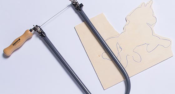 Laubsäge und Sperrholzplatte mit aufgezeichnetem Einhorn